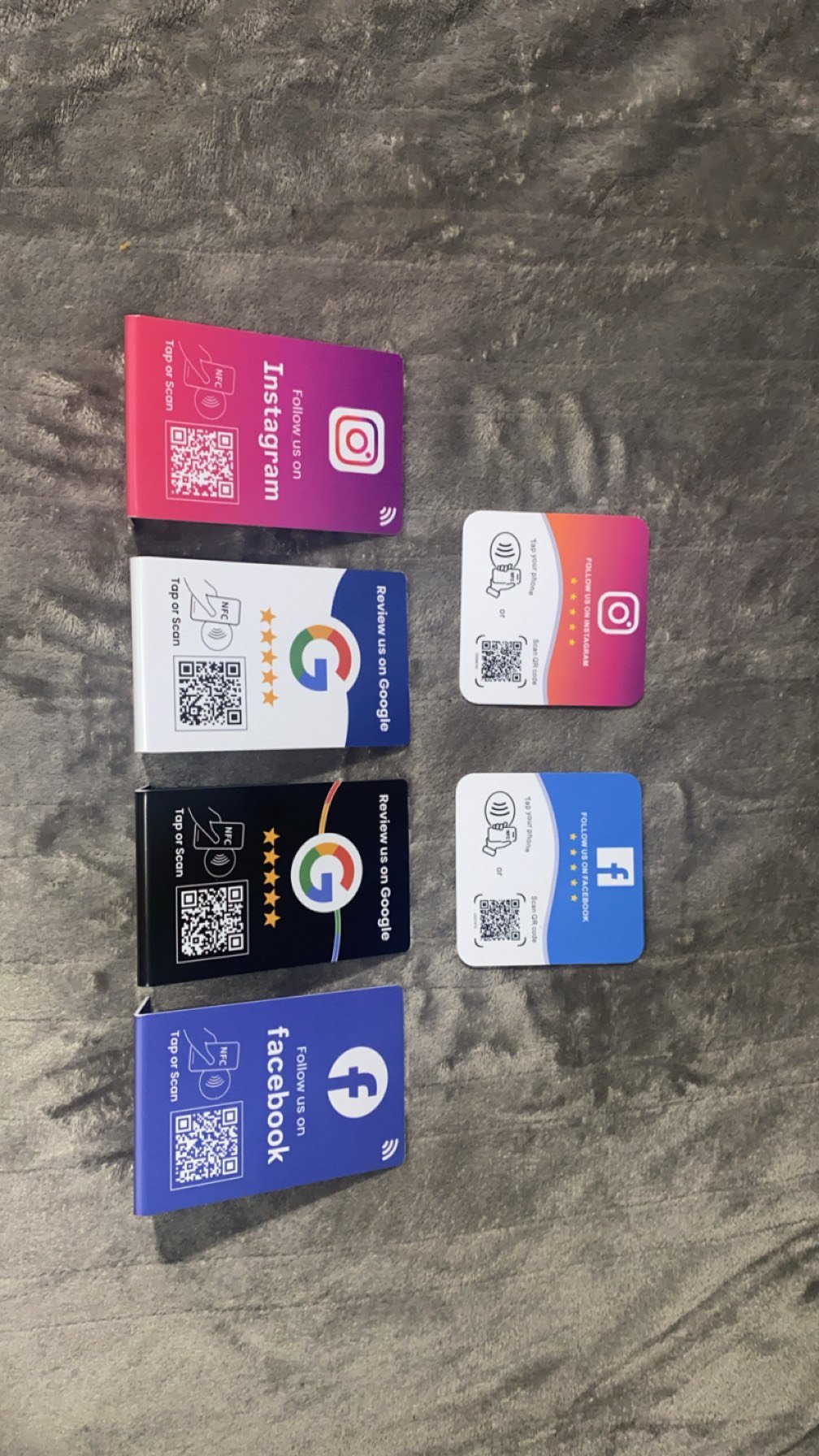Collection of social media NFC business cards with QR codes for Instagram, Google, and Facebook on concrete surface