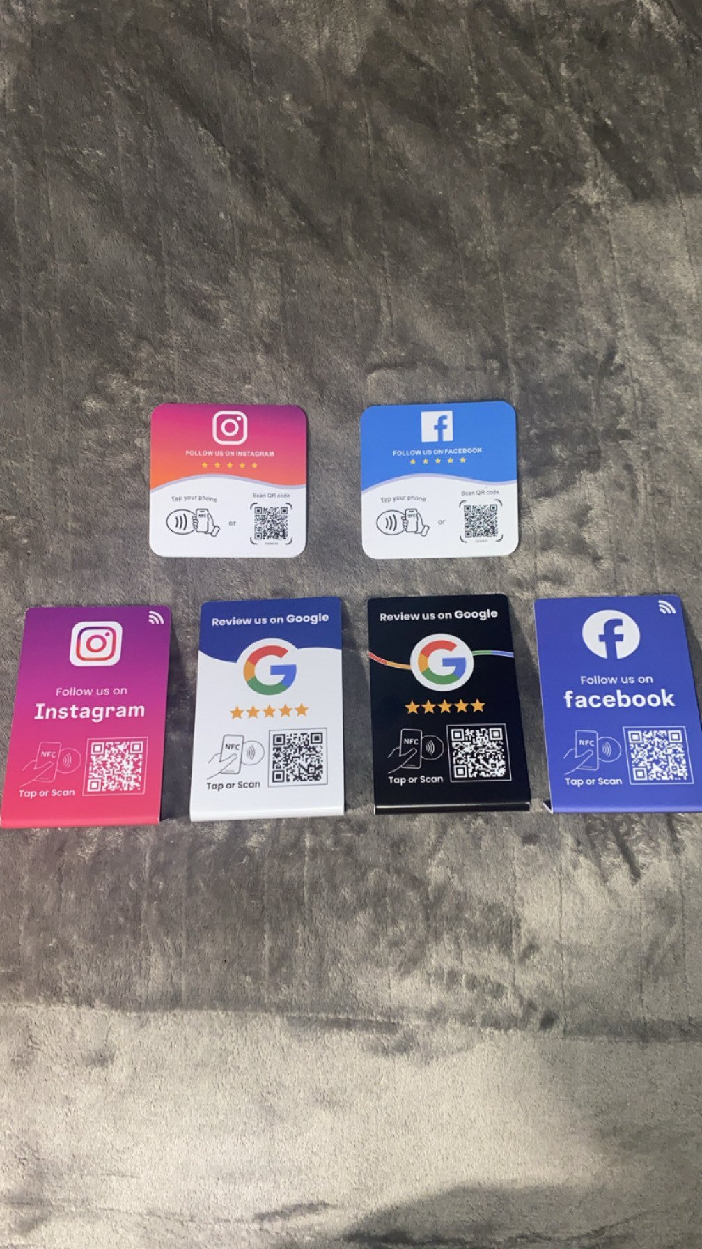 Five social media NFC tap cards displayed on textured gray surface, including Instagram, Facebook, and Google Review cards with QR codes